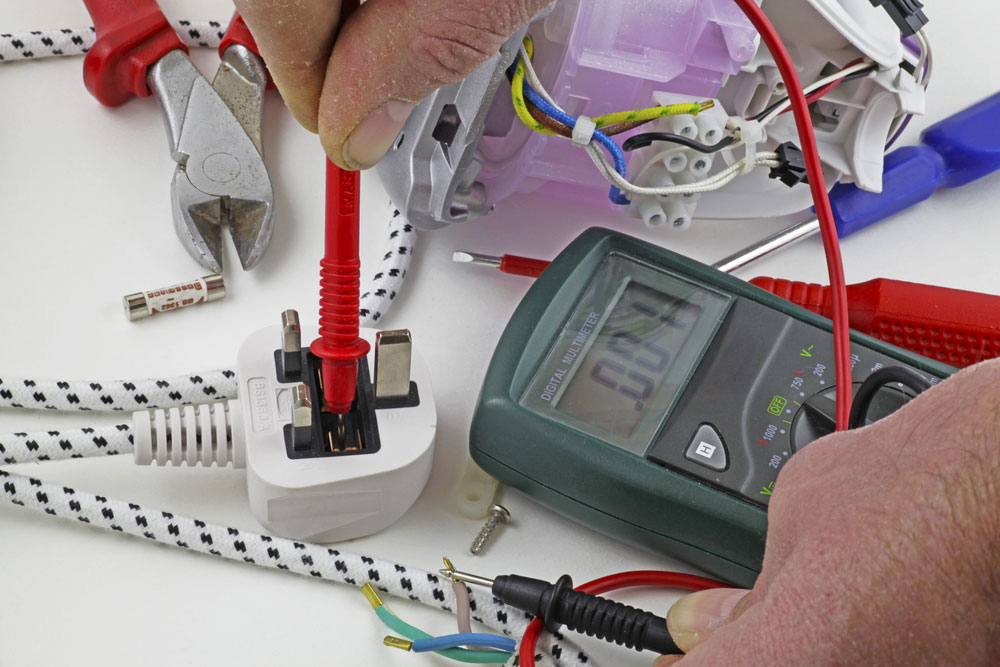 an electrician testing for a fault on the live cable with a multimeter